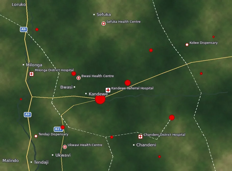 Satellite-style map with towns, roads A9 and B27, and health facilities from dispensaries to Kandewe Referral Hospital; red circles sized by emergency case volume with flashing dots marking live emergencies.
